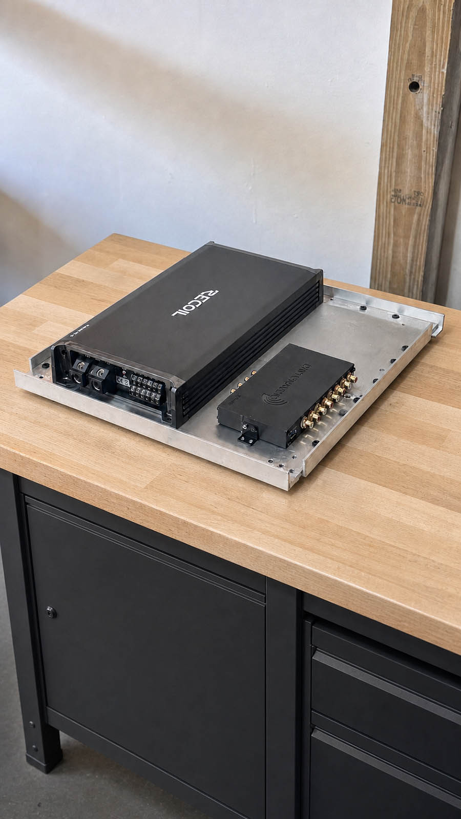 Three-quarter view of a prototype amplifier and DSP mounting drawer on a workbench.